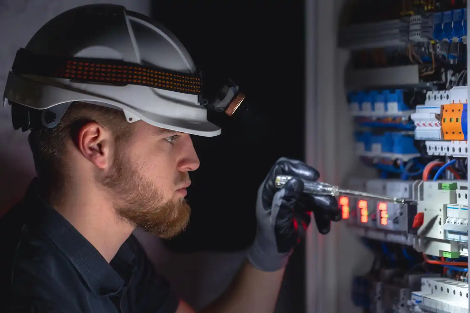 24/7 electrician working on electrical panel at night